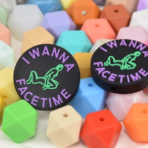 May include: Black round beads with the text "I WANNA FACETIME" in purple and a green graphic. The beads are surrounded by colorful geometric beads in various pastel shades, including pink, blue, and yellow.