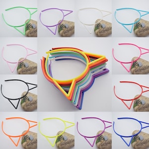 K&ouml;nnte beinhalten: Ein Set mit 12 bunten Plastik-Haarreifen mit Katzenohren-Akzenten. Die Haarreifen sind in verschiedenen Farben erh&auml;ltlich, darunter Pink, Blau, Gr&uuml;n, Gelb, Orange und Lila.
