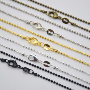 May include: Assortment of ball chain necklaces in black, silver, gold, and bronze. Each chain has a lobster clasp closure.