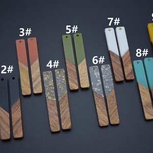 May include: Nine pairs of wooden earrings with different colored resin tops. The earrings are numbered 1 through 9. The resin tops are red, orange, black, gold, green, white, gray, teal, and yellow.