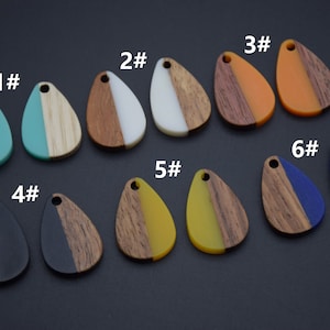 Pode incluir: Seis pares de pingentes de madeira em forma de lágrima com inserções de resina de diferentes cores. Os pingentes são numerados de 1 a 6.