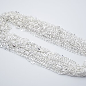 May include: A pile of silver chain, a popular material for jewelry making.