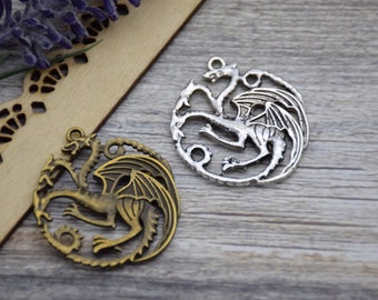 May include: Two silver dragon charms, one with a bronze finish. The dragon charms are detailed and intricate, with wings and claws. The charms are perfect for jewelry making or crafting.