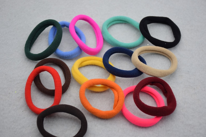 May include: A collection of colorful hair ties in various shades of red, orange, yellow, green, blue, brown, and black. The hair ties are made of soft, stretchy fabric and are perfect for holding back hair.