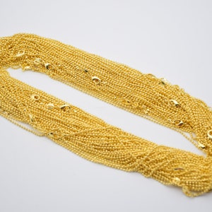 May include: A large pile of gold-colored chain links. The chain is made of small, round links.