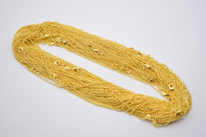 May include: A large pile of gold-colored chain links. The chain is made of small, round links.