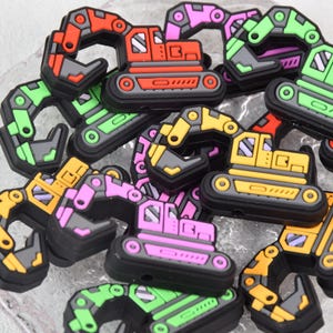 Può includere: Una collezione di veicoli da costruzione giocattolo colorati, tra cui escavatori, bulldozer e camion ribaltabili. I giocattoli sono in gomma e hanno un design da cartone animato.