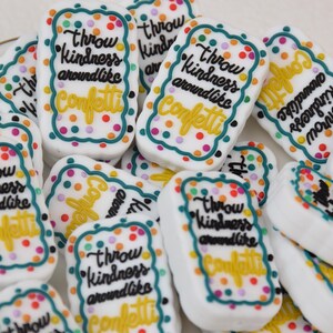 Könnte beinhalten: Eine Sammlung weißer rechteckiger Fliesen mit einem bunten Konfetti-Muster und dem Text "Throw kindness around like confetti" in schwarzer Schrift.