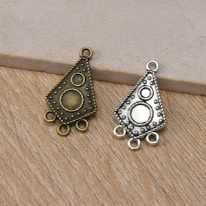 May include: Two metal pendant charms with a geometric design. One charm is antique brass and the other is silver. Both charms have three loops at the bottom.