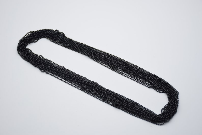 May include: A bulk pack of black ball chain, a type of chain commonly used for necklaces, keychains, and other jewelry.