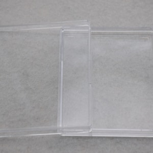 May include: Two clear plastic storage boxes stacked on top of each other. The boxes are rectangular and have a smooth, glossy finish.