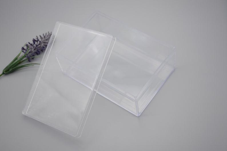 Pode incluir: Uma caixa de pl&aacute;stico transparente com tampa. A caixa &eacute; retangular e tem uma superf&iacute;cie lisa. A tampa &eacute; ligeiramente inclinada e encaixa perfeitamente na parte superior da caixa.