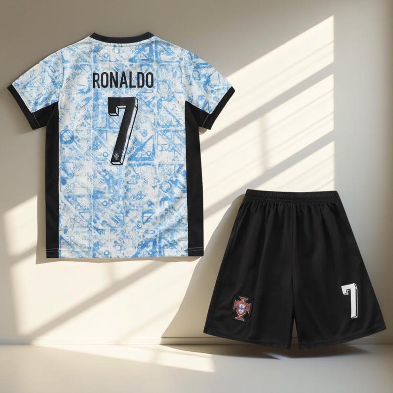May include: A white and blue soccer jersey with black trim and the name "RONALDO" and the number "7" on the back. A black soccer short with a white "7" and the Portuguese crest on the side.