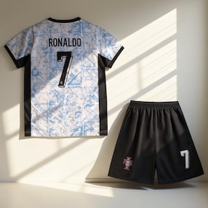 May include: A white and black soccer jersey with a blue and white pattern. The jersey has the name "RONALDO" and the number "7" on the back. A black soccer short with the number "7" and the Portuguese crest on the side.
