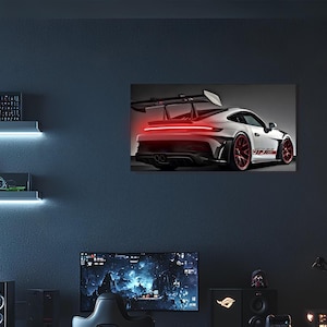 Puede incluir: Un Porsche 911 GT3 RS blanco con detalles rojos y un alerón trasero negro. El coche está aparcado en una superficie negra y las luces traseras están encendidas.