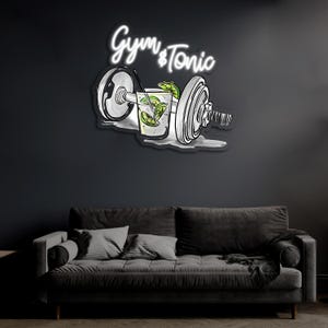 May include: White neon sign with the text "Gym & Tonic" and a drawing of a dumbbell with a glass of gin and tonic in the middle.
