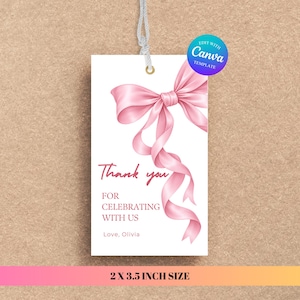 May include: A rectangular white gift tag measuring 5.08 by 8.89 cm with a pink ribbon illustration and the text Thank you FOR CELEBRATING WITH US Love, Olivia. The tag features a gold eyelet and a silver string at the top for hanging purposes.