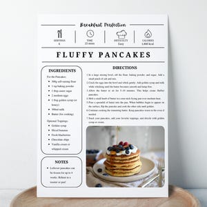 K&ouml;nnte beinhalten: Rezeptkarte f&uuml;r "Fluffy Pancakes" mit Zutaten und Anweisungen. Die Karte zeigt einen Stapel Pfannkuchen mit Blaubeeren und Sirup. Das Rezept ist f&uuml;r 4 Portionen und dauert 25 Minuten.