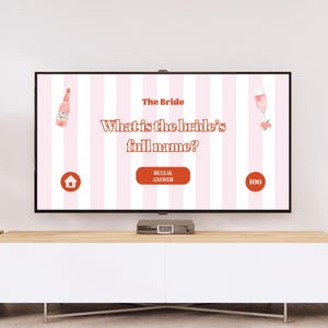May include: A pink and white striped screen displaying a bridal shower game. The question is "What is the bride's full name?" with a pink bottle of champagne, a pink champagne flute, and a pink flower on the screen. The screen also has a button that says "Reveal Answer" and a score of 100.