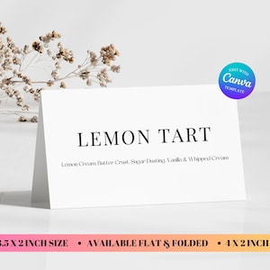 May include: A white card displays "LEMON TART" in a bold font, with ingredients listed below. The card is folded and stands upright. A sprig of dried flowers is in the background. The card is 3.5 x 2 inches and 4 x 2 inches.
