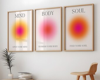 Peut inclure: Trois impressions encadrées avec un motif de cercle dégradé dans des tons de rose, orange et jaune. Les impressions portent les mots "MIND", "BODY" et "SOUL" en haut et une phrase correspondante en bas : "OPEN YOUR MIND", "NOURISH YOUR BODY" et "FEED YOUR SOUL".