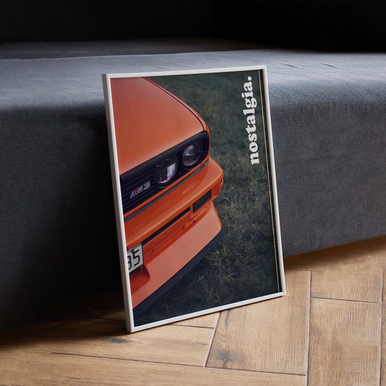 May include: A close-up of an orange car with black headlights and the word "nostalgia" printed on the side. The car is parked on a grassy surface.