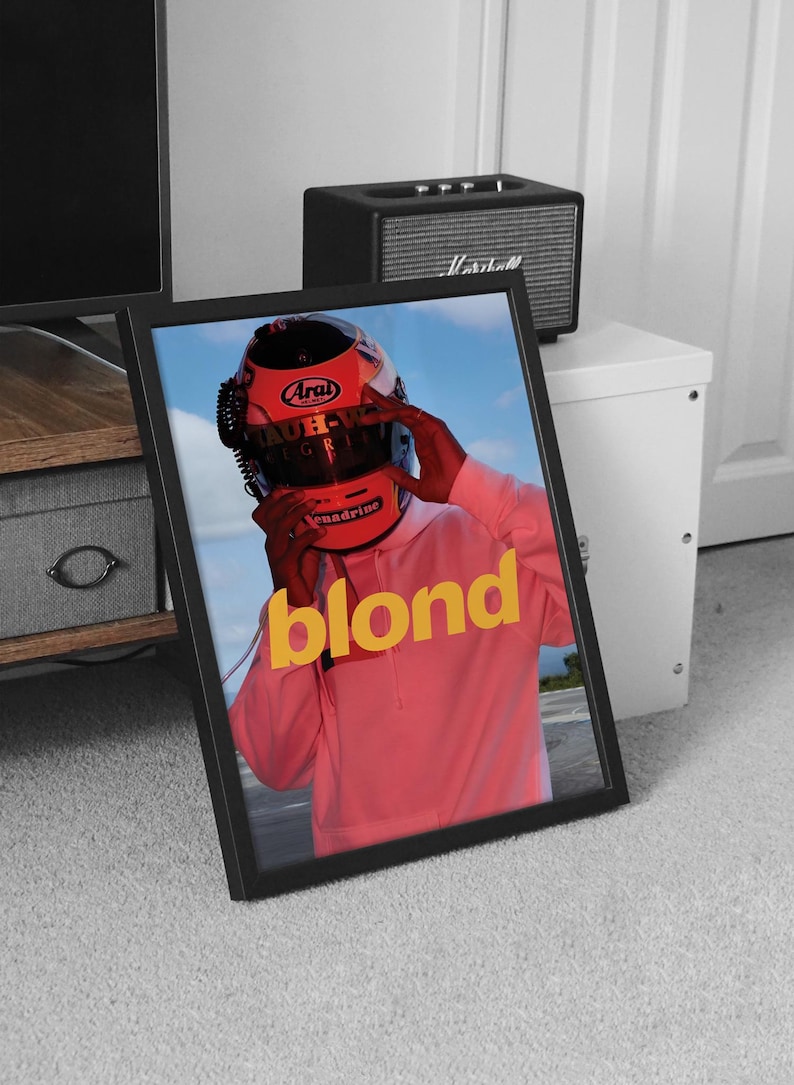 May include: A framed poster featuring a photograph of a person wearing a red racing helmet with the word "blond" in yellow lettering on a pink background.