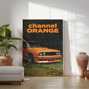May include: A poster featuring the text "channel ORANGE" in orange lettering against a black backdrop. A vibrant orange car is partially visible in the bottom right corner of the poster.