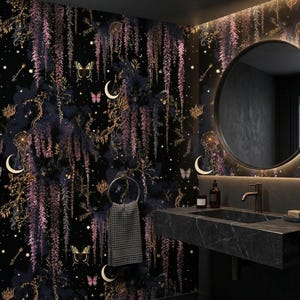 Könnte beinhalten: Ein Badezimmer mit einem dunklen, himmlischen Thema. Die Wände sind mit Tapeten bedeckt, die ein Nachthimmel-Design mit Monden, Schmetterlingen und hängenden floralen Elementen in Lila und Gold zeigen. Über einem Waschbecken aus schwarzem Marmor befindet sich ein runder Spiegel.