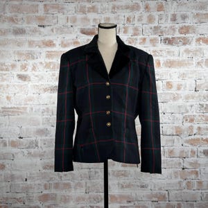 May include: A dark green plaid blazer with red and green accents, displayed on a mannequin. The blazer features a black velvet collar, gold buttons, and a tailored fit. The jacket is a classic style, suitable for various occasions.