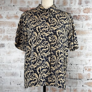 May include: A short-sleeved button-up shirt with a black and gold floral pattern. The shirt is made of a silky fabric and has a classic collar.