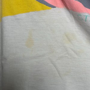 This image showcases a close up view of some of the staining present on the front side of a true vintage 1980s salvage condition thrashed Belton Tough Tee women’s 100% preshrunk cotton St. Thomas single stitch graphic t-shirt in a size XL modeled on a dress form.