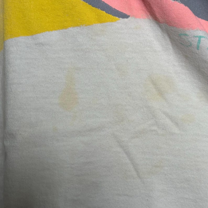 This image showcases a close up view of some of the staining present on the front side of a true vintage 1980s salvage condition thrashed Belton Tough Tee women’s 100% preshrunk cotton St. Thomas single stitch graphic t-shirt in a size XL modeled on a dress form.