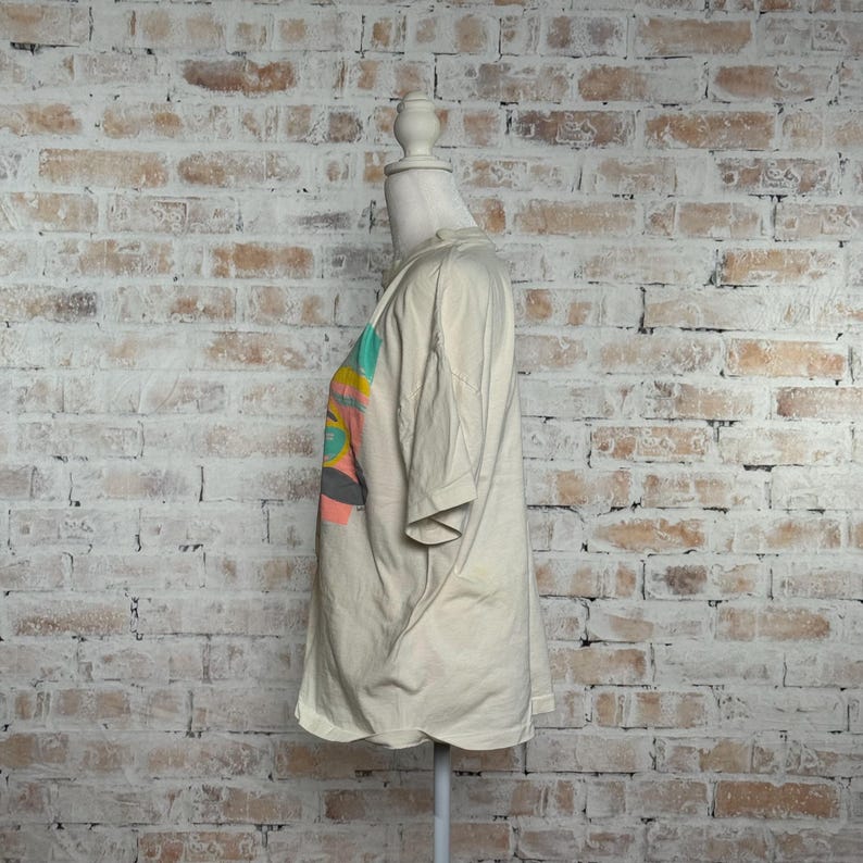 This image showcases the entire right side of a true vintage 1980s salvage condition thrashed Belton Tough Tee women’s 100% preshrunk cotton St. Thomas single stitch graphic t-shirt in a size XL modeled on a dress form in front of a brick backdrop.
