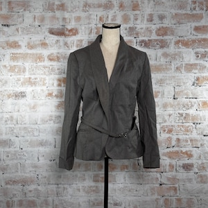 May include: A gray blazer with a long, pointed collar and a belt at the waist. The blazer has a single button closure and long sleeves.
