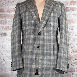 May include: A gray blazer with a blue and white plaid pattern. The blazer has a patch pocket on the left side and two button closures.
