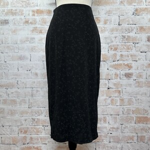 May include: A black midi skirt with a floral pattern. The skirt is made of a soft, stretchy fabric and has a fitted silhouette.