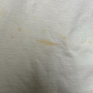 This image showcases a close up view of some of the staining present on the front side of a true vintage 1980s salvage condition thrashed Belton Tough Tee women’s 100% preshrunk cotton St. Thomas single stitch graphic t-shirt in a size XL modeled on a dress form.