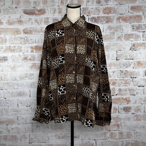 May include: A long-sleeved button-up shirt with a patchwork design featuring various animal prints in shades of brown, black, and white.