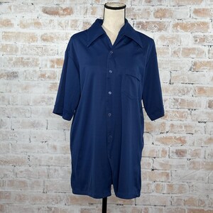 May include: A navy blue short-sleeved button-down shirt with a single pocket on the left chest.