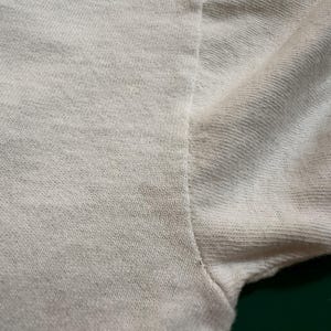 This image showcases a close up view of the graying present at the right underarm seam of a true vintage 1980s salvage condition thrashed Belton Tough Tee women’s 100% preshrunk cotton St. Thomas single stitch graphic t-shirt in a size XL.