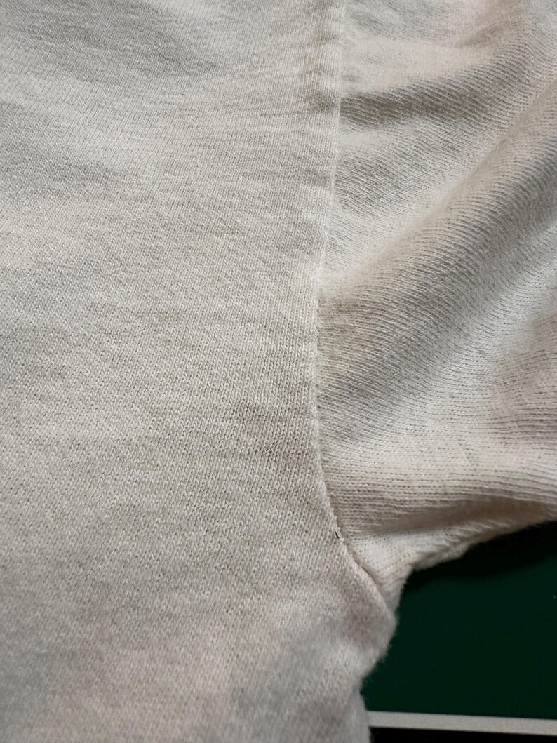 This image showcases a close up view of the graying present at the right underarm seam of a true vintage 1980s salvage condition thrashed Belton Tough Tee women’s 100% preshrunk cotton St. Thomas single stitch graphic t-shirt in a size XL.