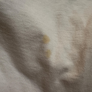 This image showcases a close up view of some of the staining present on the back side of a true vintage 1980s salvage condition thrashed Belton Tough Tee women’s 100% preshrunk cotton St. Thomas single stitch graphic t-shirt in a size XL modeled on a dress form.
