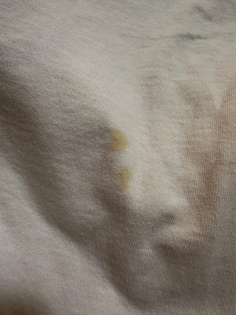 This image showcases a close up view of some of the staining present on the back side of a true vintage 1980s salvage condition thrashed Belton Tough Tee women’s 100% preshrunk cotton St. Thomas single stitch graphic t-shirt in a size XL modeled on a dress form.