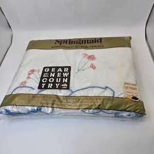May include: A twin flat sheet in a plastic package. The sheet is white with a floral pattern in pink and blue. The package has the text "Springmaid Wondercale No-Iron Percale" and "Gear New Country". The sheet measures 66 x 96 inches.