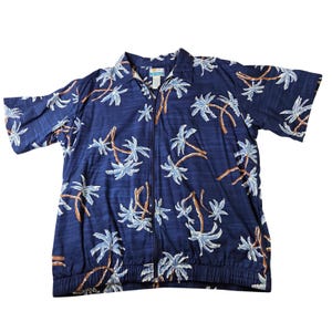 May include: A navy blue short-sleeve shirt with a full-length zipper and a palm tree pattern. The shirt features a light blue and brown palm tree design. The shirt has a collared neckline and a ribbed hem.
