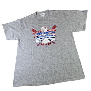 May include: A gray t-shirt featuring a graphic for the New York Yankees Opening Day 2004. The design includes baseball bats, a baseball, and the team's logo. The shirt is made by Adidas.