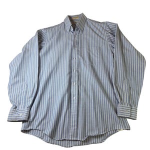 Puede incluir: Una taza de cerámica blanca con asa negra y el texto "But First, Coffee" en negrita negra. La taza se encuentra sobre un fondo borroso, sugiriendo un ambiente acogedor.