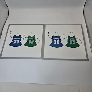 May include: Two square artworks feature whimsical figures wearing basketball jerseys. One figure wears a blue jersey with the number 20, and the other wears a green jersey with the number 03. The jerseys read "Timberwolves" and "Lynx".