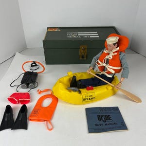 May include: A G.I. Joe action figure in a yellow life raft with accessories. The figure wears a sailor hat and orange life vest. Accessories include binoculars, fins, and a navy manual.